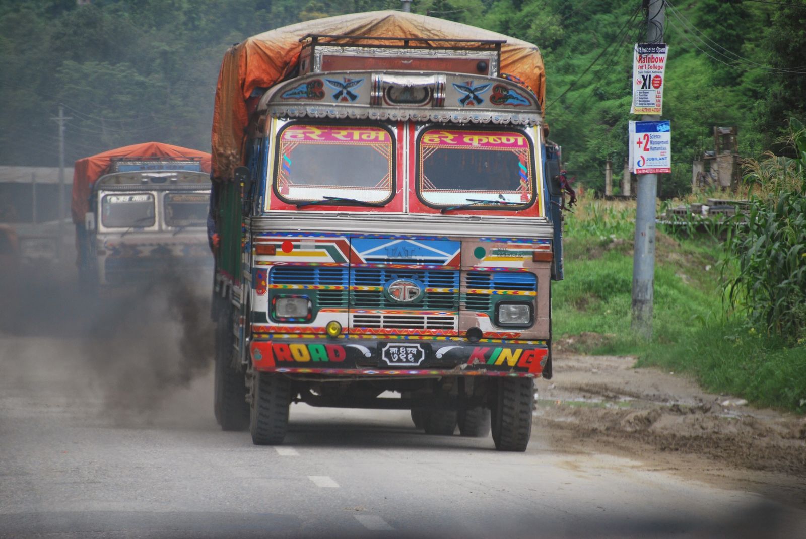 Camión nepalí decorado con colores vivos circulando por una carretera de montaña polvorienta