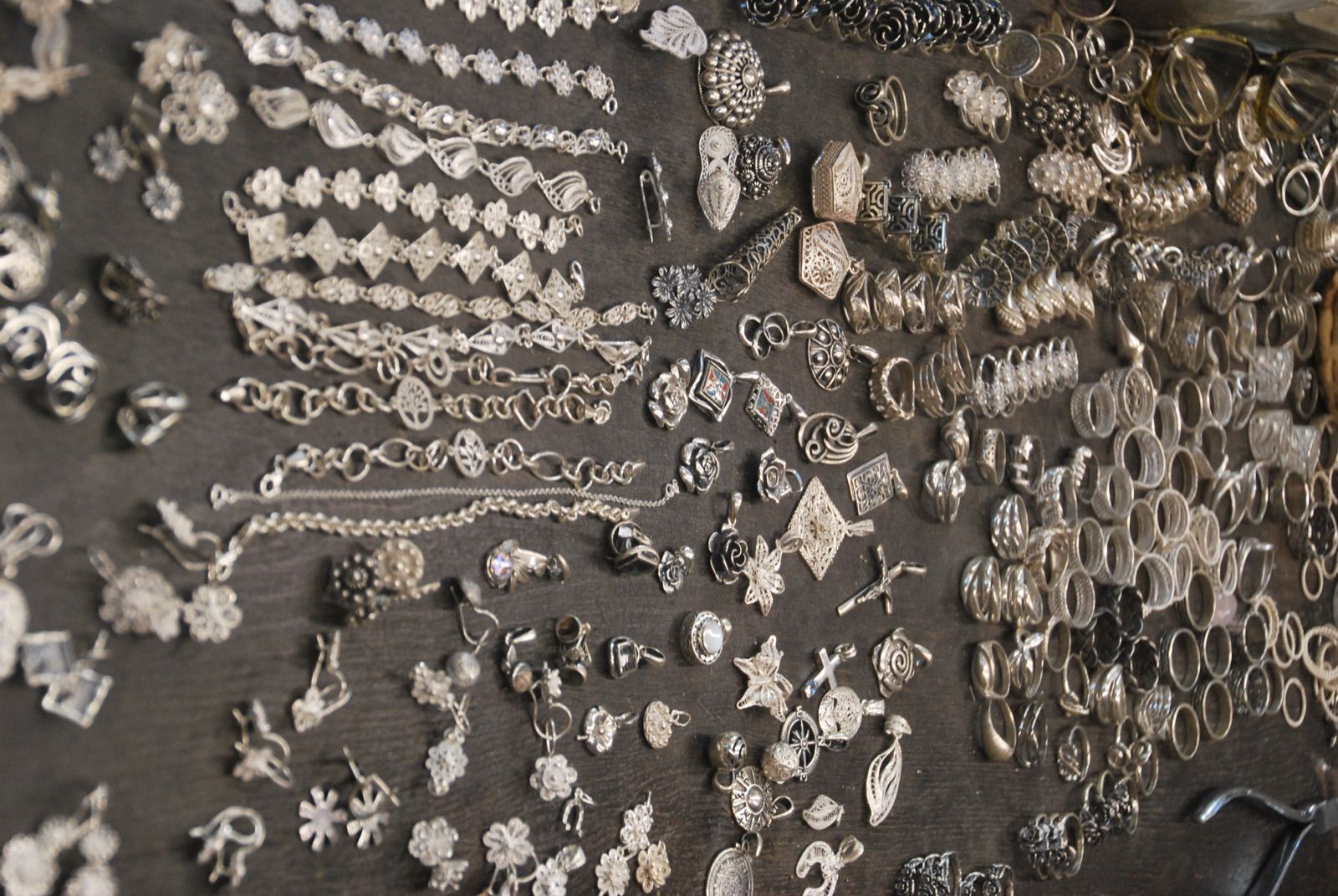 Mesa de taller cubierta de anillos, colgantes y pulseras de filigrana de plata