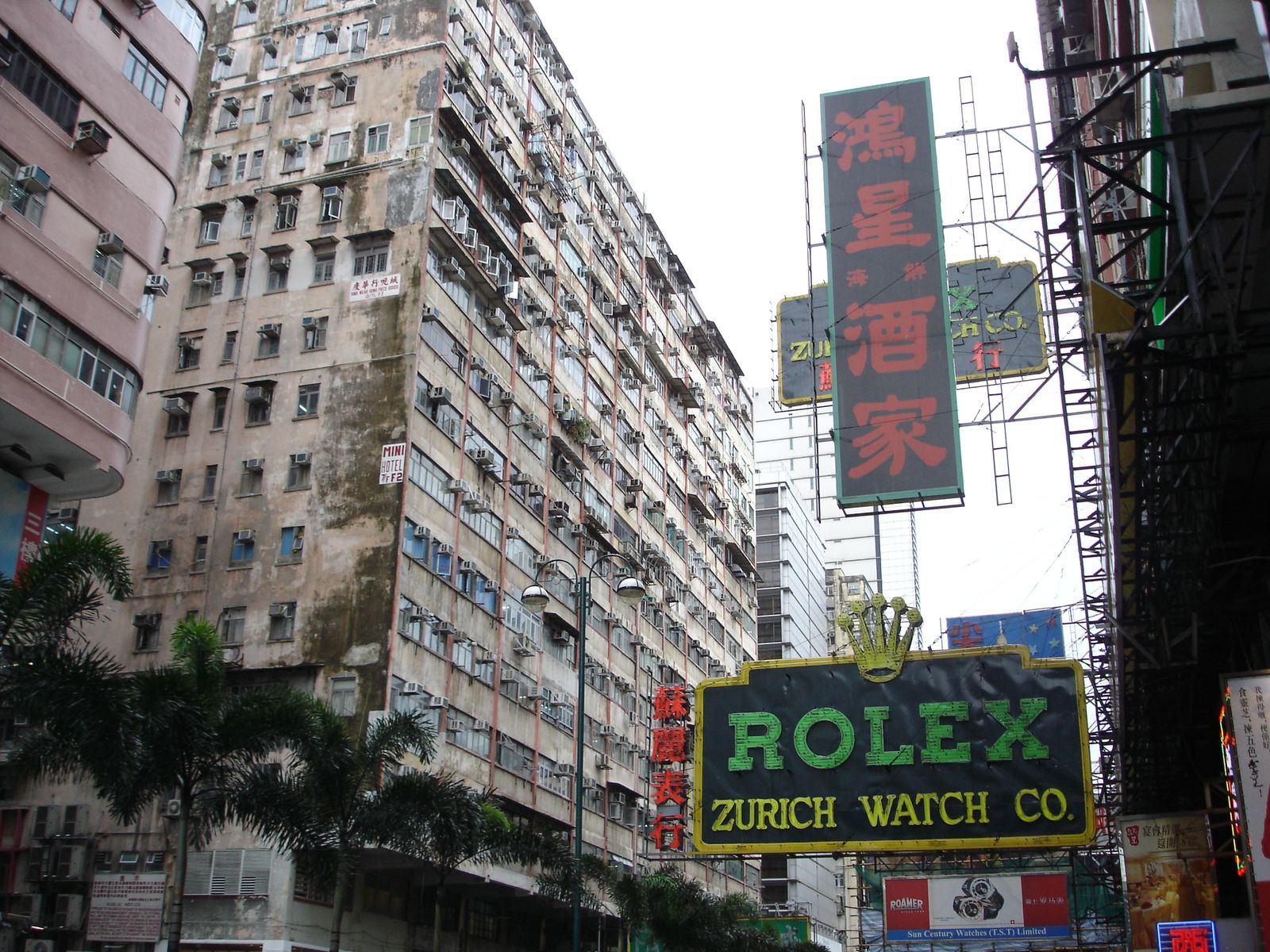 Calle de Kowloon con fachadas densas y letreros comerciales superpuestos