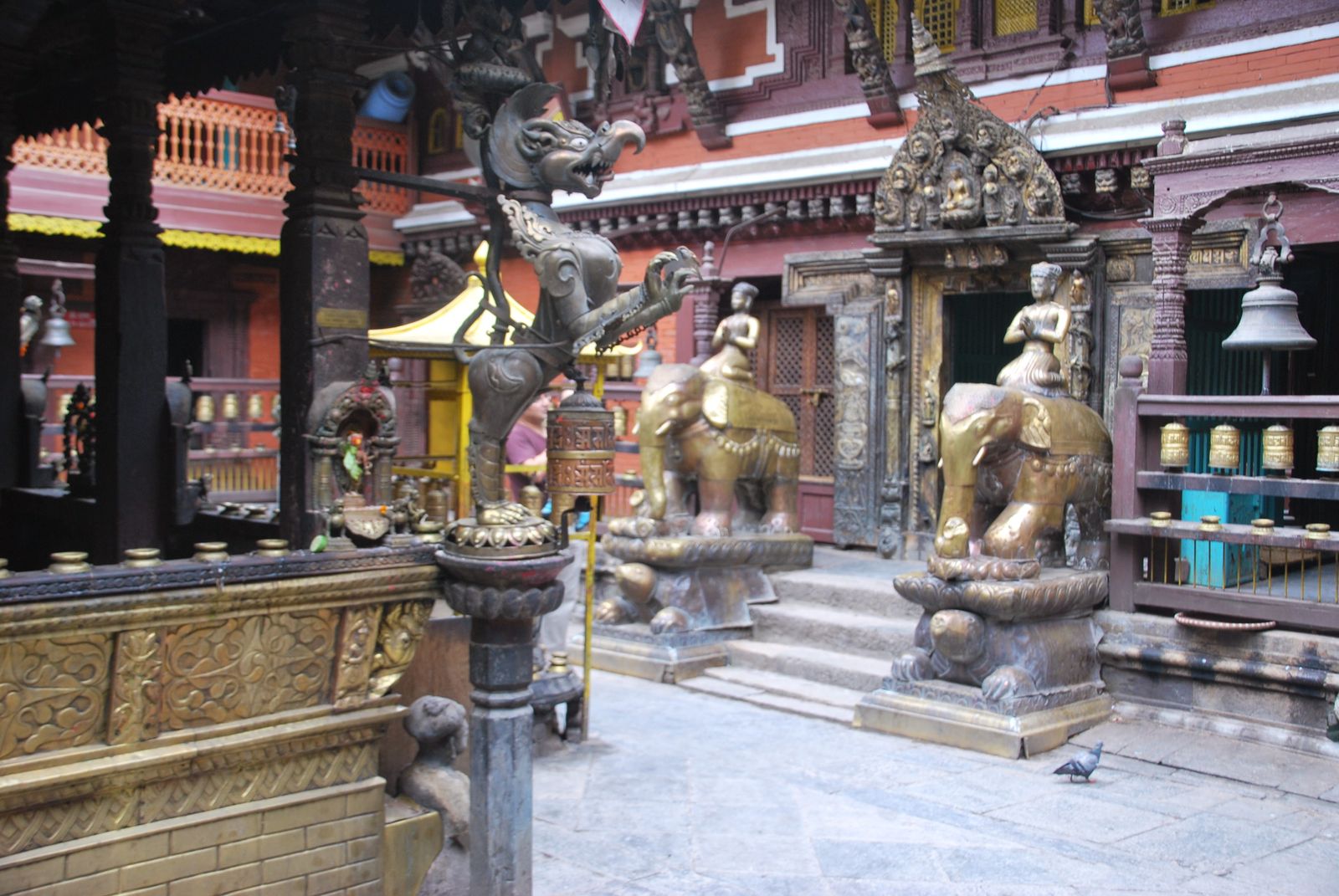 Estatuas doradas y campanas a la entrada de un templo hinduista de Katmandú