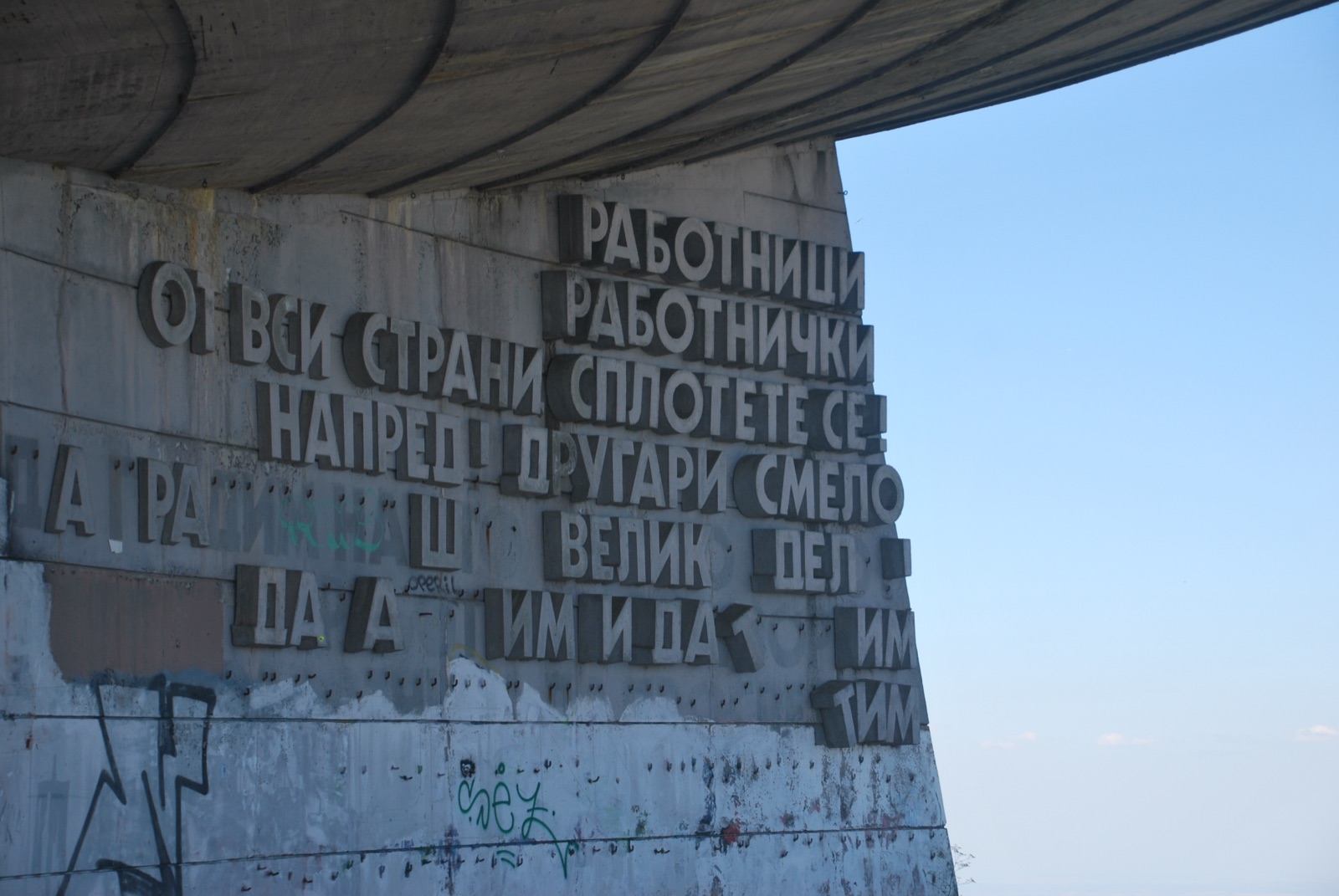 Letras cirílicas de hormigón, parcialmente caídas, en la fachada curva del monumento de Buzludzha