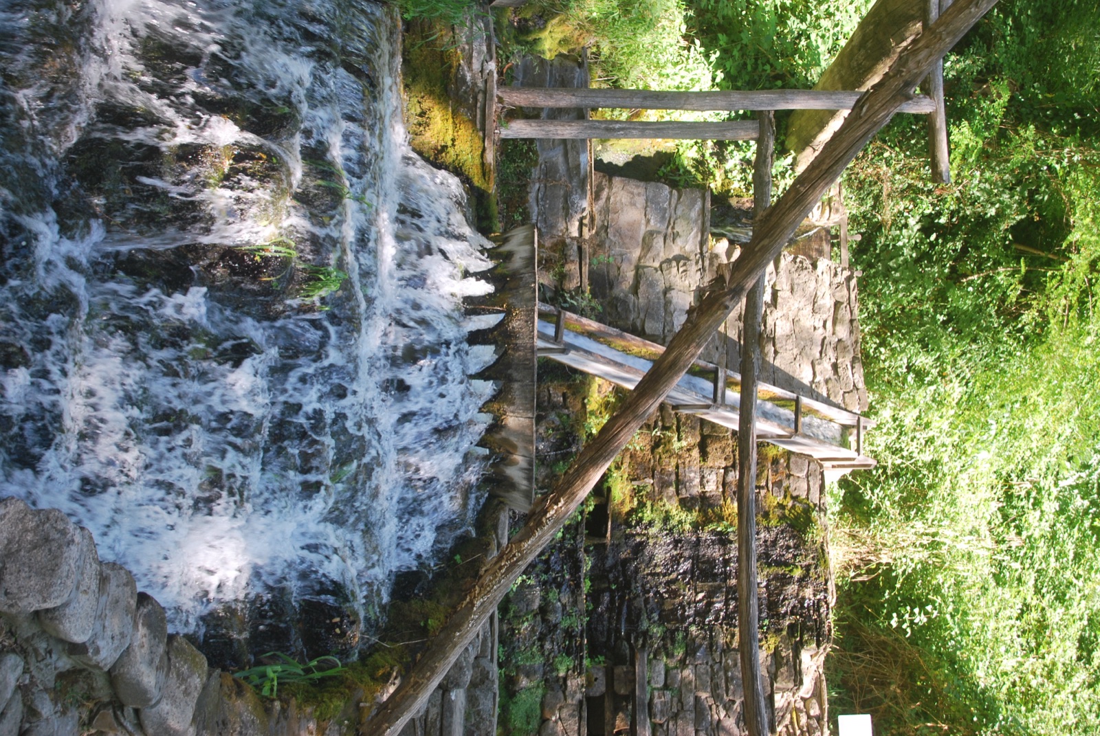 Canal de madera que vierte agua sobre una cascada entre muros de piedra en el complejo de Etar