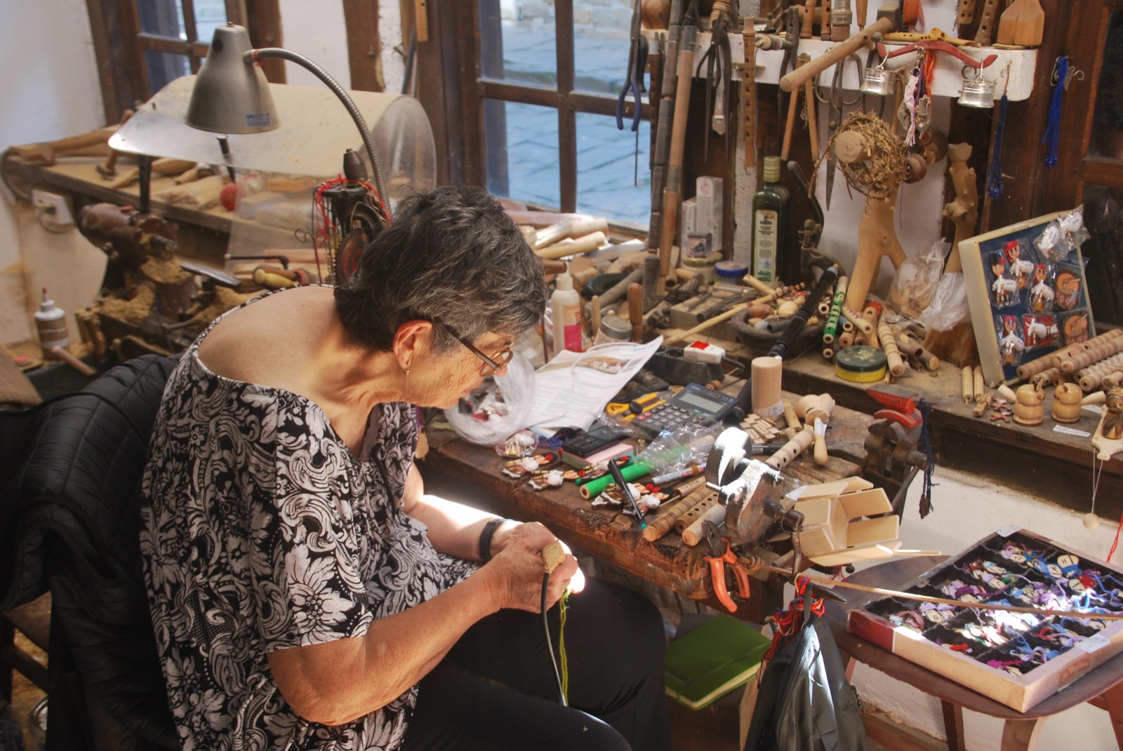 Artesana trabajando entre herramientas, flautas y juguetes de madera en su taller de Etar