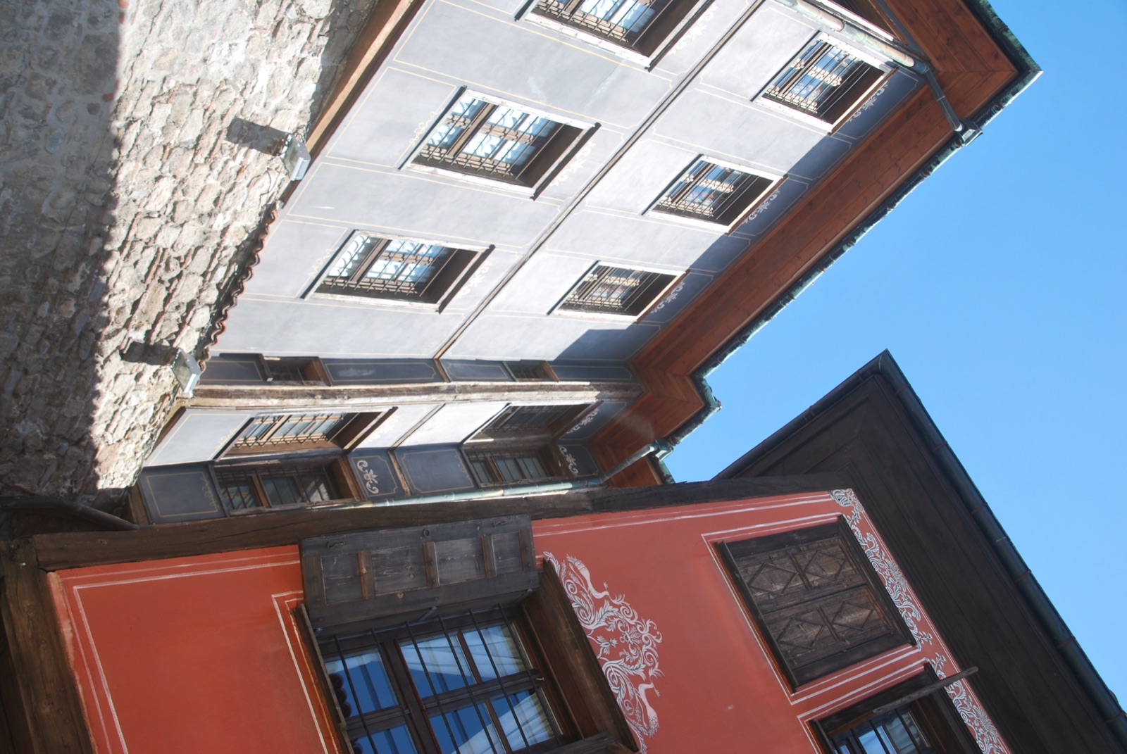 Dos casas del Renacimiento búlgaro, una gris y otra roja con decoración pintada, voladas sobre la muralla de piedra de Plovdiv