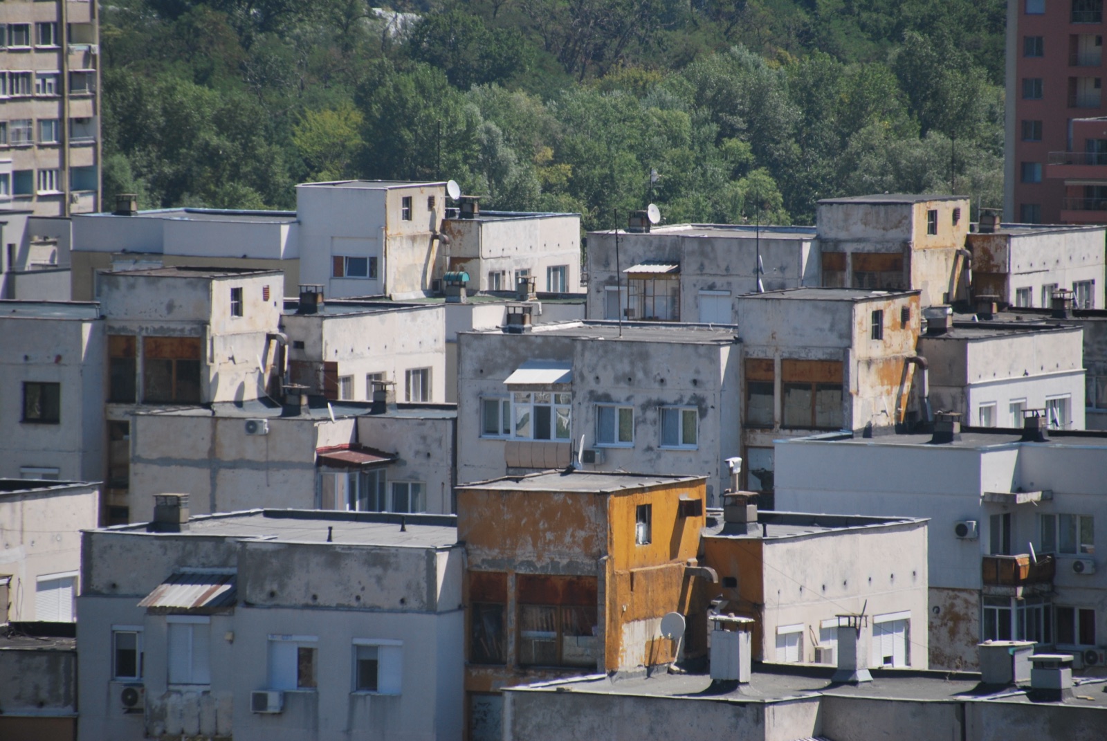 Bloques de viviendas desgastados de la periferia de Plovdiv vistos con teleobjetivo, con fachadas despintadas y antenas