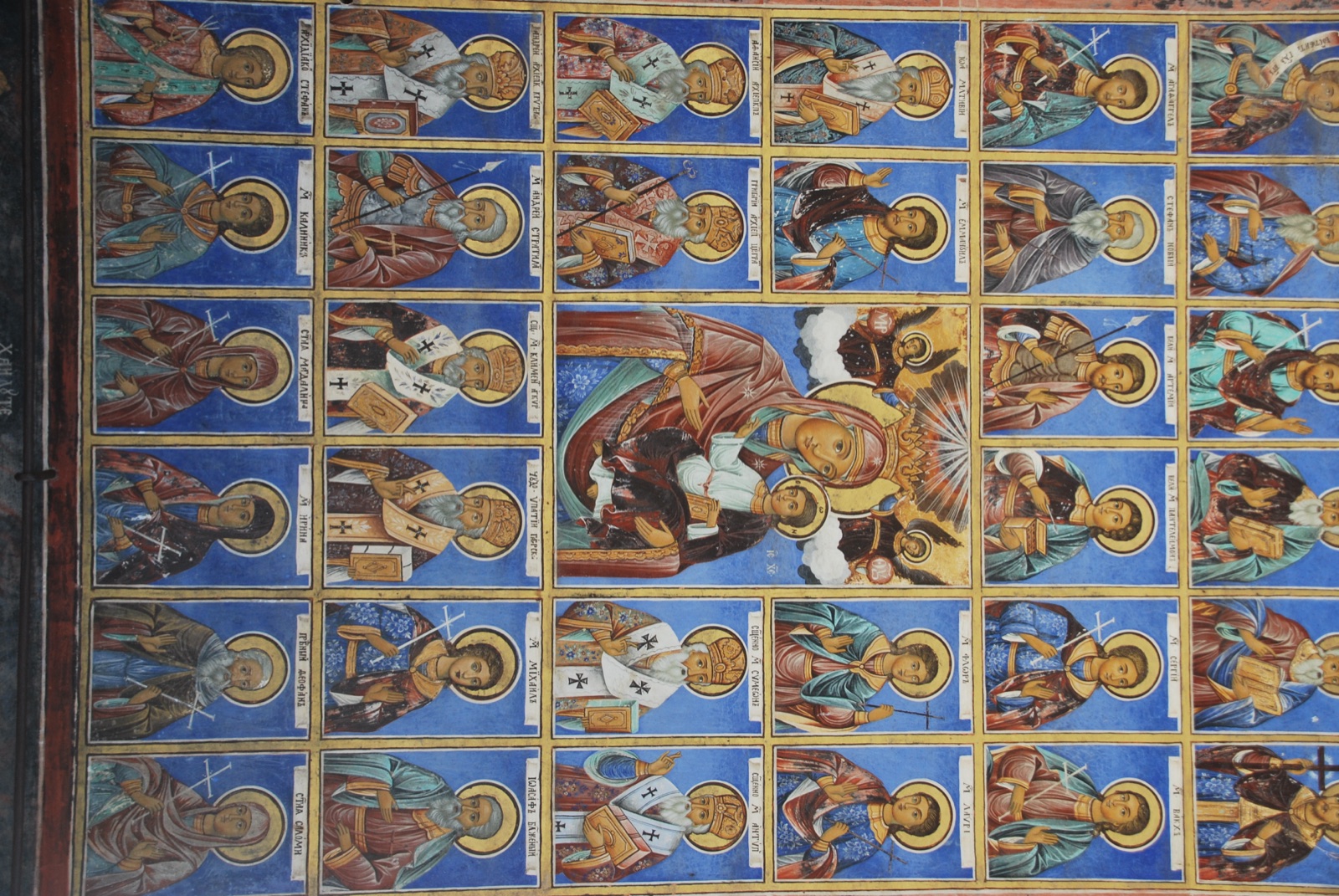 Muro exterior del monasterio de Rila cubierto por una retícula de retratos de santos ortodoxos sobre fondo azul