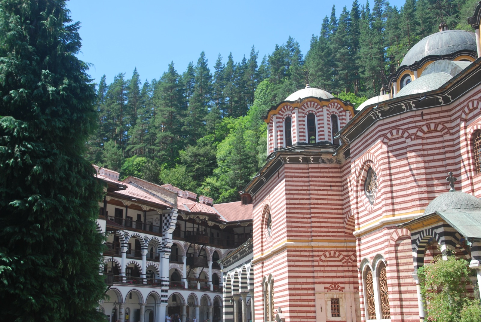 Patio del monasterio de Rila con las galerías de arcos de las celdas monásticas y el bosque de pinos que rodea el recinto
