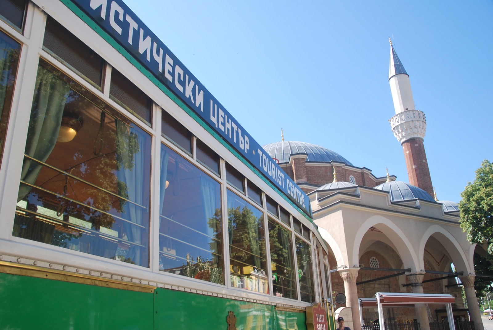 Antiguo tranvía verde reconvertido en oficina de turismo, con la mezquita Banya Bashi al fondo