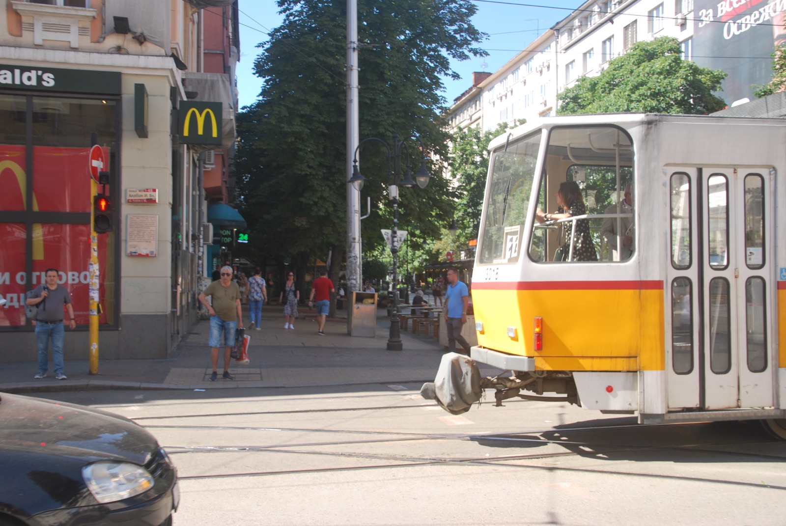 Tranvía amarillo cruzando el bulevar Vitosha ante un McDonald's, con peatones esperando en el paso