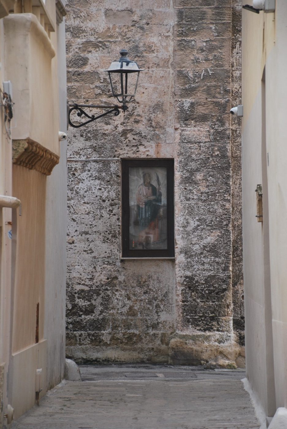 Callejón de piedra encalada con un farol en Alberobello