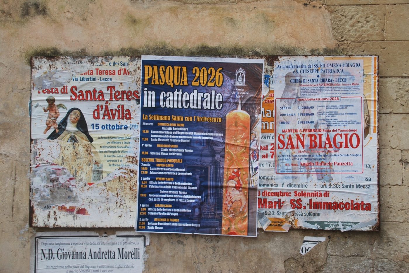 Carteles parroquiales sobre una pared encalada del casco antiguo de Lecce