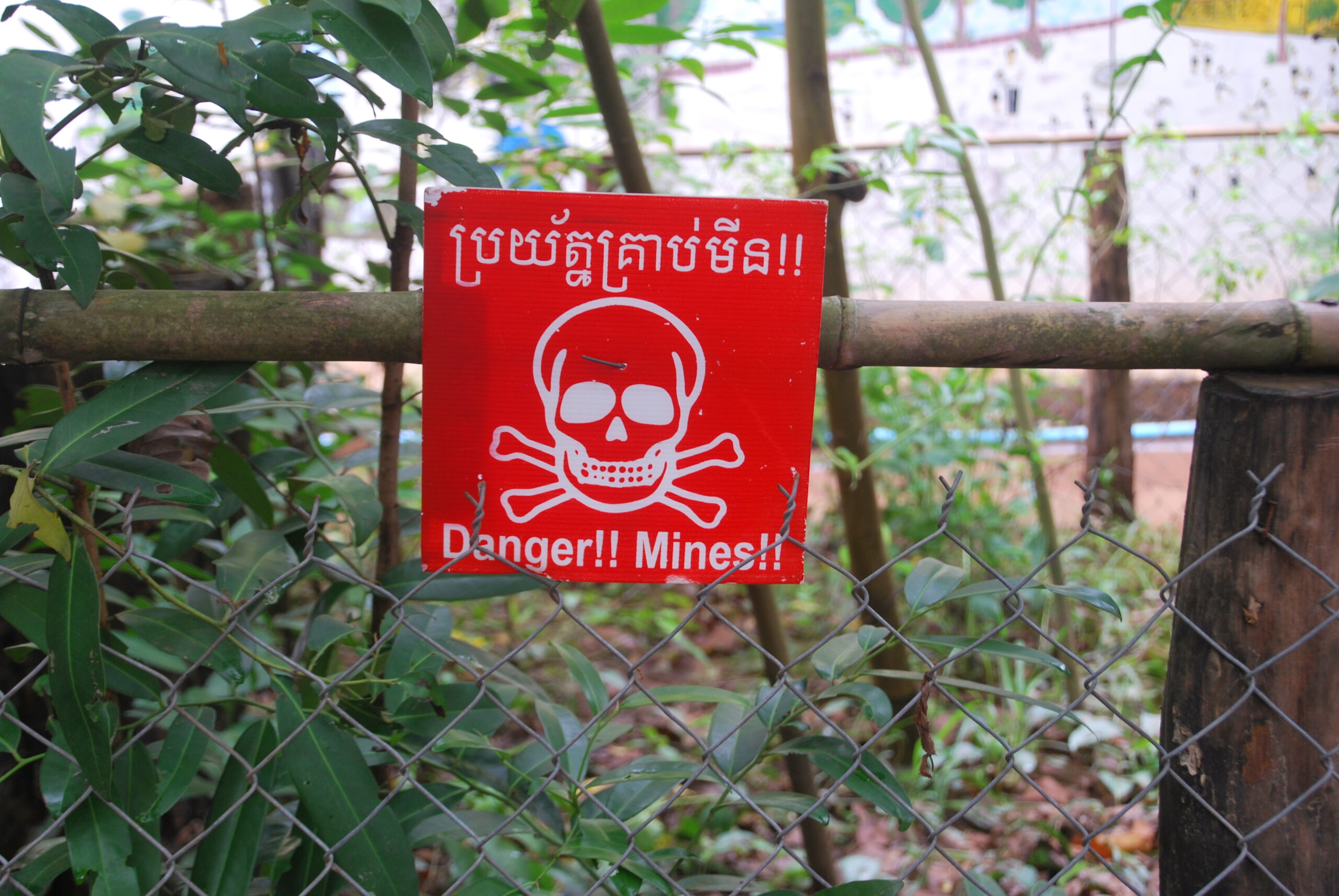 Señal de peligro de minas antipersona en khmer e inglés, valla metálica en Siem Reap