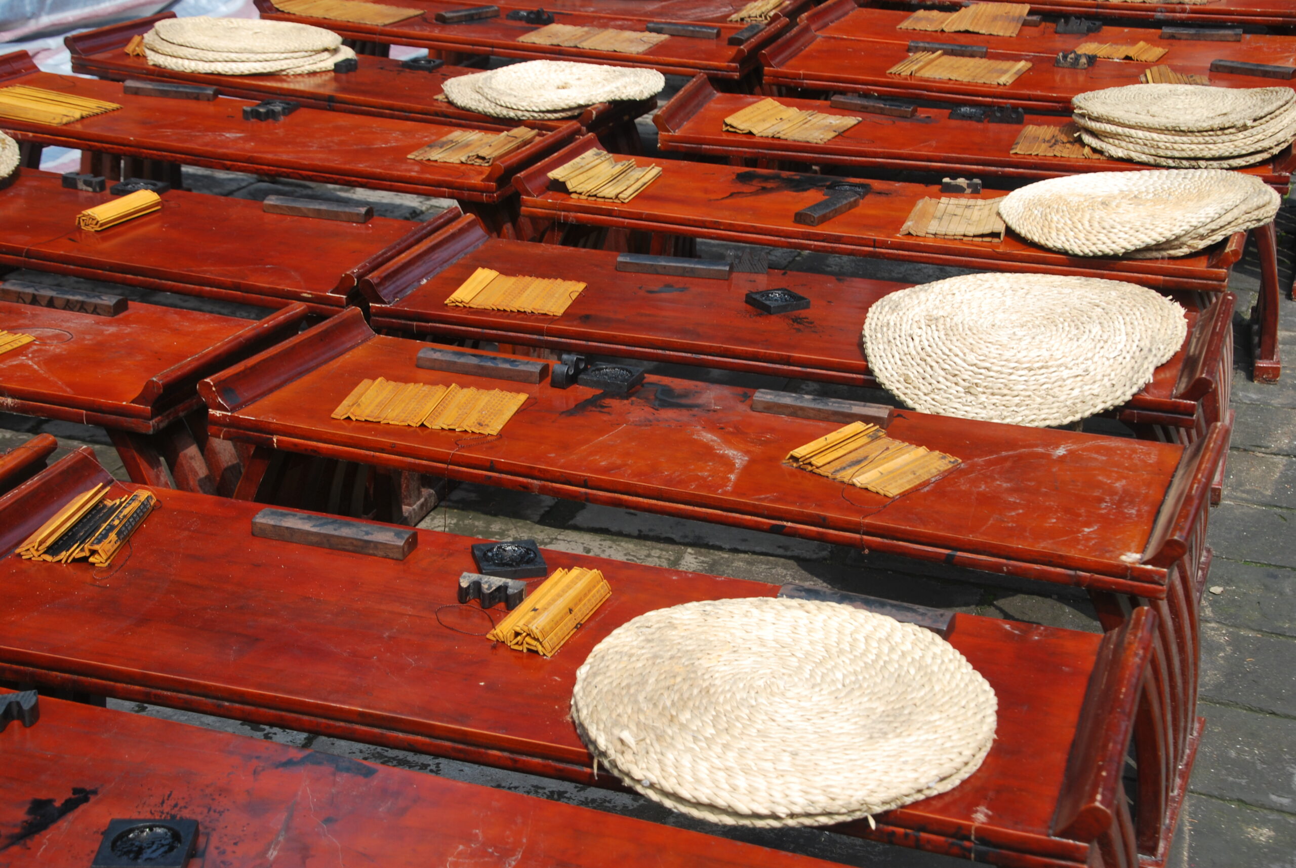 Bancos de madera roja laqueada con sombreros de paja tradicionales chinos en Xi'an