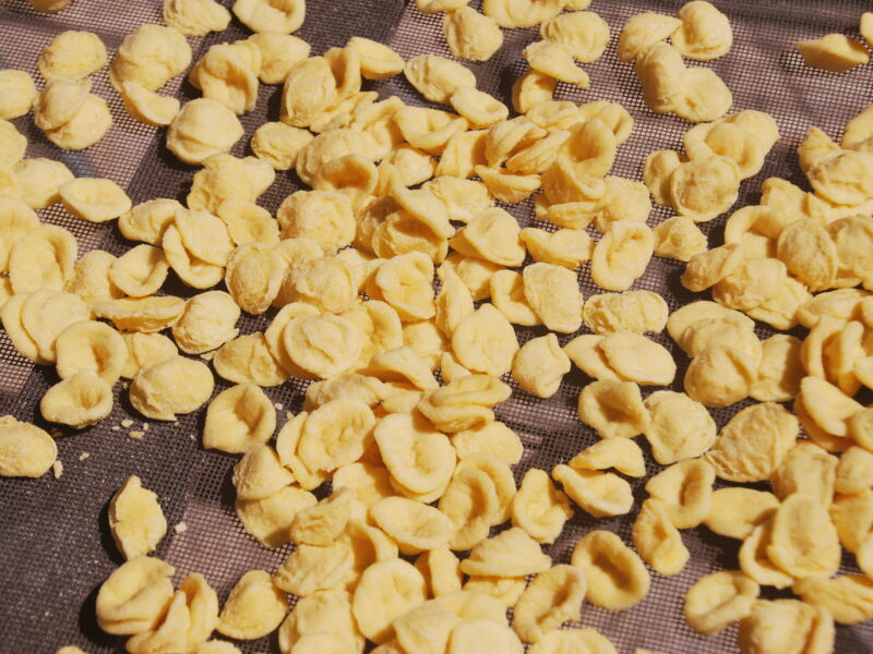 Orecchiette de Puglia hechas a mano secándose al sol sobre malla de rejilla
