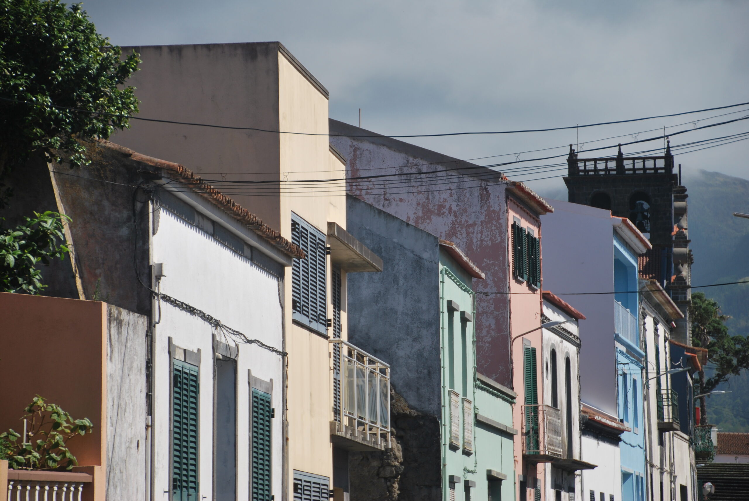 Calle con casas coloridas y torre de iglesia al fondo en São Miguel, Azores