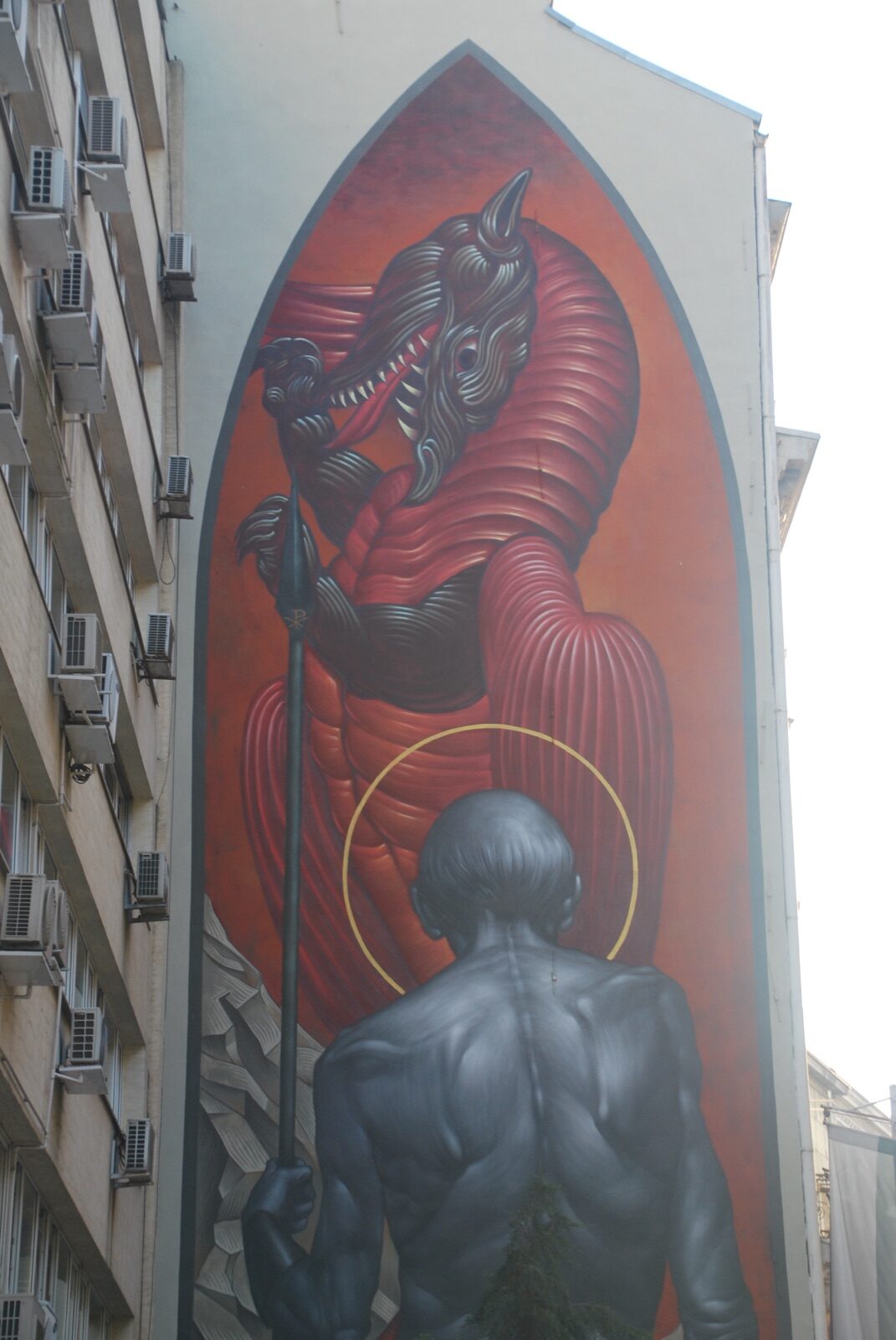 Mural de arte urbano de San Jorge y el dragón ocupando la medianera de un bloque con aires acondicionados