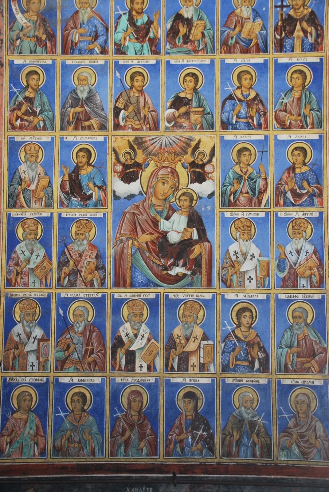 Muro exterior del monasterio de Rila cubierto por una retícula de retratos de santos ortodoxos sobre fondo azul