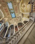 Escalera con balaustrada bajo un techo decorado con una vidriera