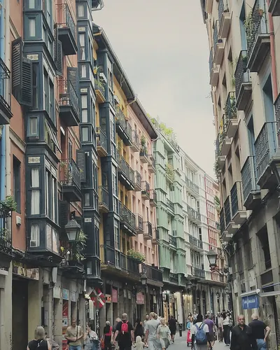 Calle con edificios de miradores acristalados y gente paseando