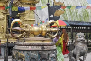 Cetro vajra dorado sobre un pedestal, con banderas de oración al fondo