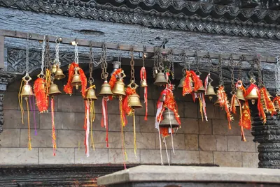 Campanas de bronce con cintas rojas colgadas bajo el alero de un templo